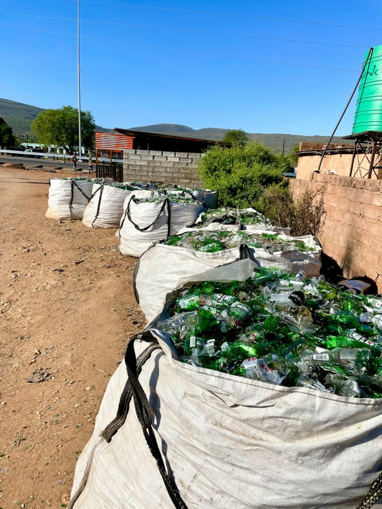 a-bunch-of-bags-filled-with-bottles-sitting-on-top-of-a-dirt-field-70v66tlmks
